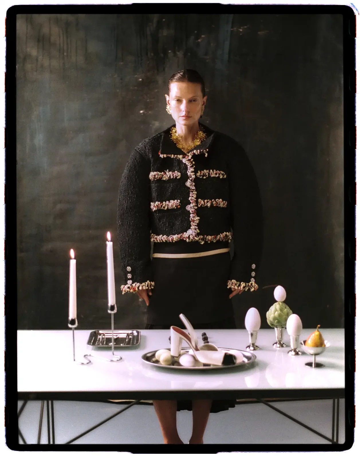 Chaqueta negra bordada frente a una mesa con candelabros — estilismo de Manel Guisado