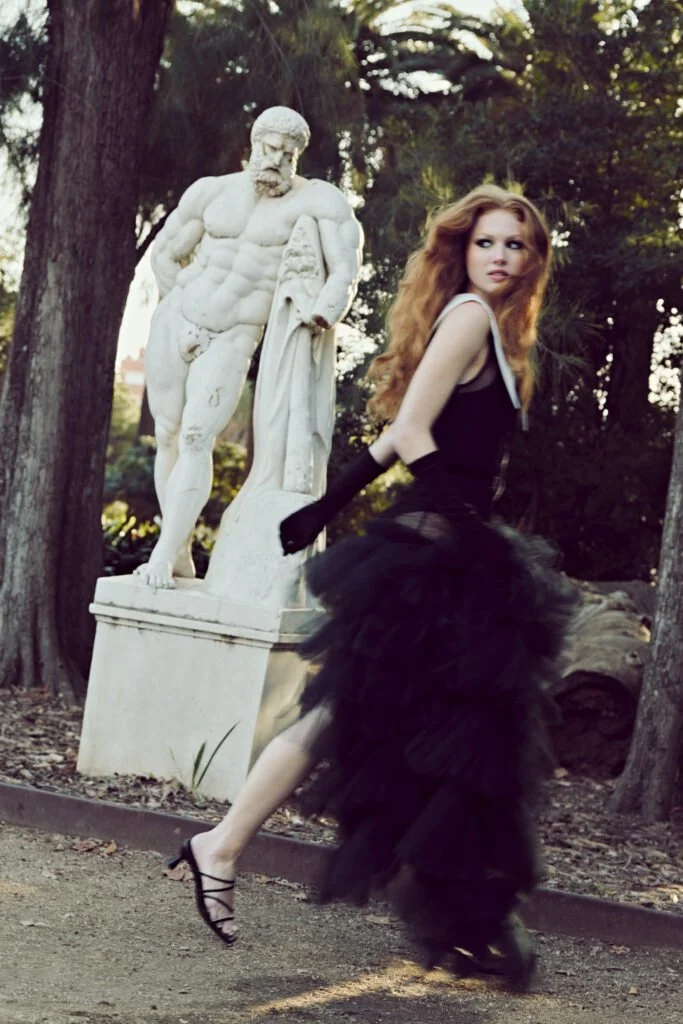 Vestido negro junto a una escultura en un jardín — estilismo de Manel Guisado