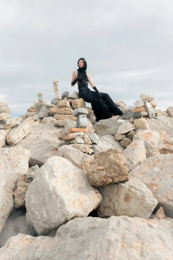Traje oscuro entre rocas junto al mar — estilismo de Manel Guisado
